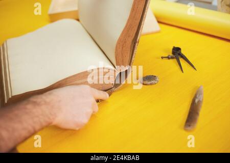 Buchbinder stellt altes Buch in Handwerkswerkstatt wieder her Stockfoto