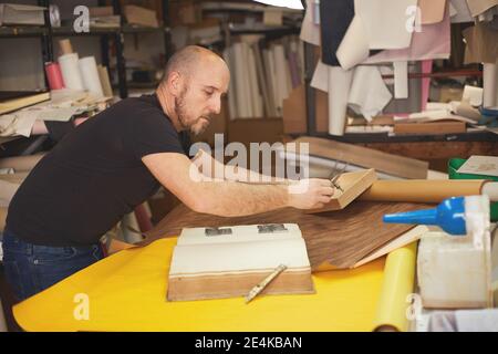 Buchbinder stellt altes Buch in Handwerkswerkstatt wieder her Stockfoto