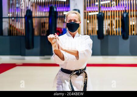 Reife Frau trägt Gesichtsmaske üben Karate im Health Club Stockfoto