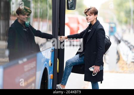 Schöner junger Mann mit Rucksack Boarding Bus in der Stadt Stockfoto