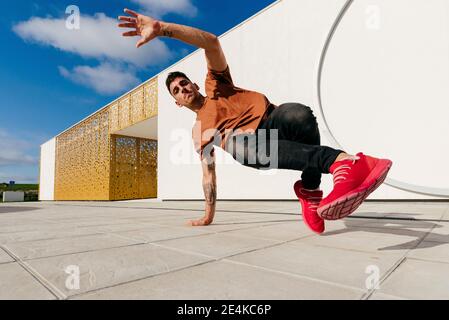 Junger Mann, der an sonnigen Tagen auf dem Fußweg tanzt Stockfoto