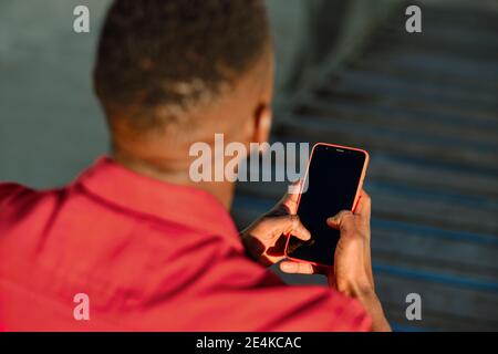 Mann in roter Jacke Blick auf Smartphone Stockfoto