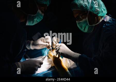 Männliche Chirurgen, die in der Notaufnahme des Krankenhauses eine Operation mit einer Schere durchführen Stockfoto