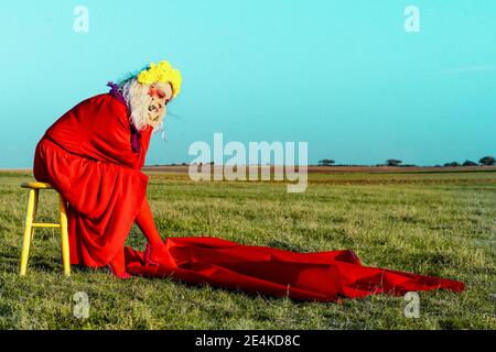 Nachdenkliche ältere Frau, die an sonnigen Tagen auf dem Tisch sitzt Stockfoto