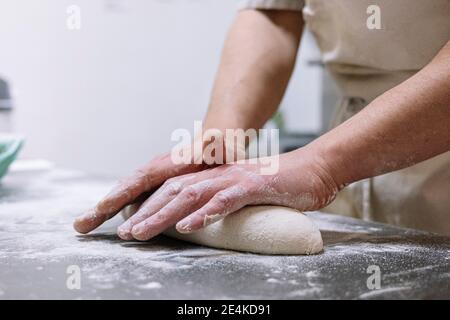 Männlicher Koch Kneten Mehlteig auf Küchentheke in der Bäckerei Stockfoto