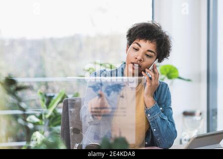 Frau am Telefon sprechen und mit transparenten Display zu Hause Stockfoto