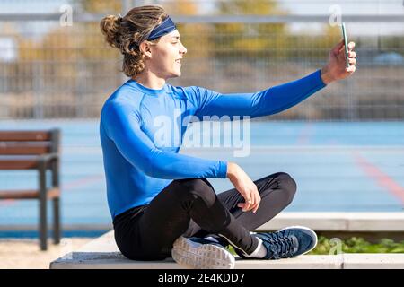 Lächelnder Sportler nimmt Selfie im öffentlichen Park an sonnigen Tag Stockfoto