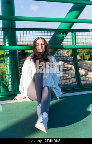 Teenager-Mädchen ruht sich aus, während sie sich auf dem Brückengeländer lehnt Stockfoto