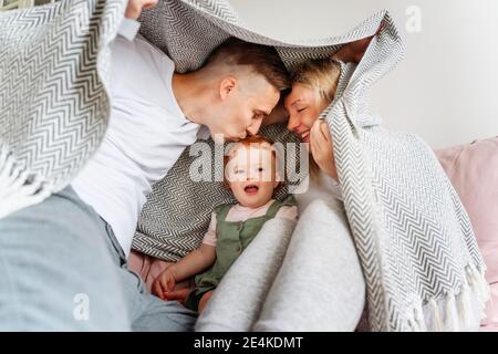 Glückliche Familie mit Baby Tochter versteckt unter Decke auf Sofa Stockfoto
