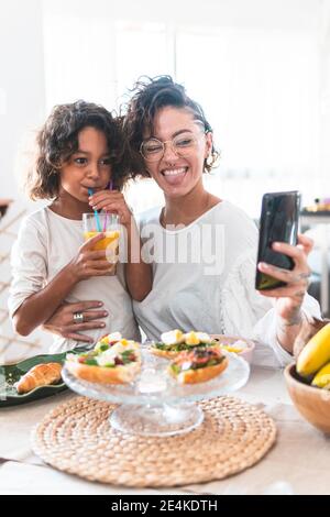 Mutter und Tochter nehmen Selfie während des Frühstücks Stockfoto