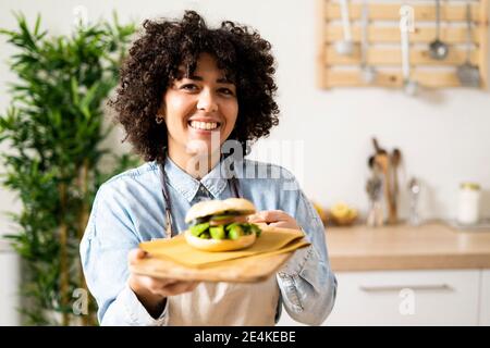 Porträt einer jungen Frau, die frisch zubereitetes veganes Sandwich hält Stockfoto