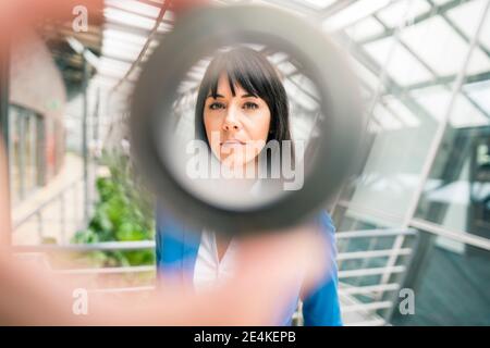 Geschäftsfrau durch die Ausrüstung im Bürokorridor gesehen Stockfoto