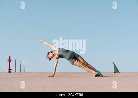 Weibliche Sportsperson üben Yoga Balancing auf einer Seite Stockfoto