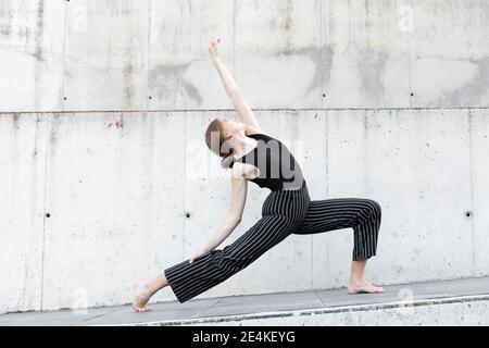 Tänzerin in schwarz gestreifter Hose vor Betonwand Stockfoto