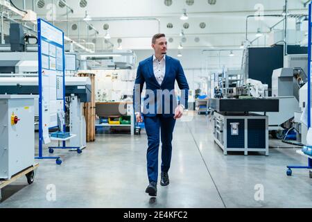 Männlicher Profi im Anzug zu Fuß in der Fabrik Stockfoto