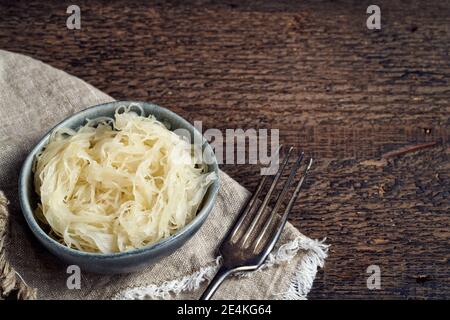 Fermentierter Kohl in einer blauen Schüssel auf einem hölzernen Hintergrund Mit Kopierbereich Stockfoto