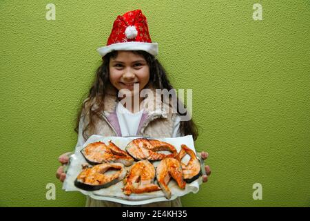 Kleines Mädchen mit einem Tablett mit gegrilltem Lachs. Stockfoto