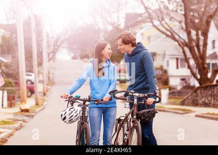 Junges Paar gehen und eng reden halten Fahrräder auf der Straße in den USA Stockfoto