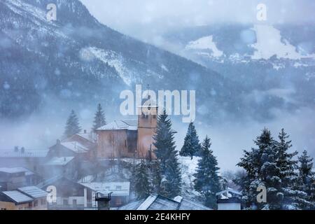 Kirche in Champagny-en-Vanoise Dorf in Frankreich und Blick auf Courchevel Bei starkem Schneefall im Winter Stockfoto