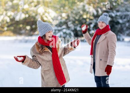 Fröhliches junges Paar mit Schneeballschlacht im Freien Stockfoto