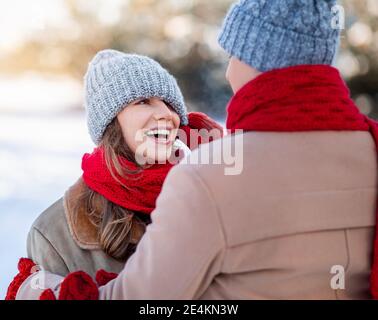Liebevoller Mann, der seine lachende Freundin Eishut herunterzieht Stockfoto