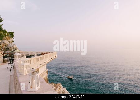Ein Holzmotorschiff fährt in der Nähe der Insel Sveti Stefan in Montenegro. Blick von oben. Das Konzept eines luxuriösen, reichen Lebens. Stockfoto