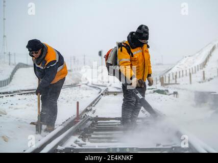 (210124) -- EMIN, 24. Januar 2021 (Xinhua) -- Wang Tianbin (L) und sein Arbeitskollege des Tiechanggou-Reparaturteams entfernen manuell Schnee vom Eisenbahnschalter in Emin, nordwestlich der Autonomen Region Xinjiang Uygur in China, 20. Januar 2021. Maytas, genannt 'Hölle des Windes', ist ein wildes Gebiet, in dem die Karamay-Tacheng-Eisenbahnstrecke in Xinjiang verläuft. Es ist auch ein Ort, wo die Tiechanggou Reparatur-Team unter der China Railway Urumqi Bureau Group Co., Ltd ist auf der Uhr 24 Stunden am Tag, um einen sicheren Betrieb aller Züge vorbei zu gewährleisten.Maytas ist ein Schneesturm-Bereich selten in China und sogar ich gesehen Stockfoto