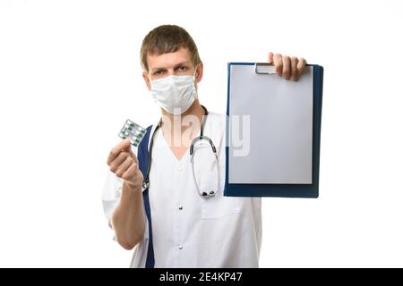 Der Arzt zeigt eine Tablette mit einem weißen Blatt Papier im Rahmen, hält Medikamente in der anderen Hand, wobei der Fokus auf die Tablette Stockfoto