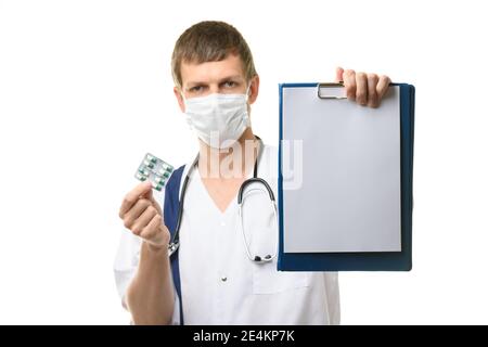 Der Arzt zeigt eine Tablette mit einem weißen Blatt Papier im Rahmen, hält Medikamente in der anderen Hand Stockfoto