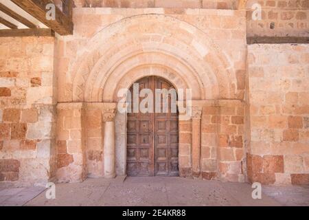 Außenfassade mit Holztür, geschmückt Bögen und Säulen, in der Kirche San Miguel (St. Michael), aus dem zwölften Jahrhundert, in Ayllon Dorf, Segov Stockfoto