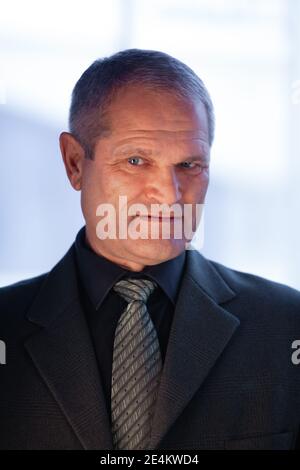 Seriöse ältere Mann Geschäftsmann in einem Anzug schrsinnig schaut in den Rahmen, vertikale Porträt, hellen Hintergrund. Hochwertige Fotos Stockfoto