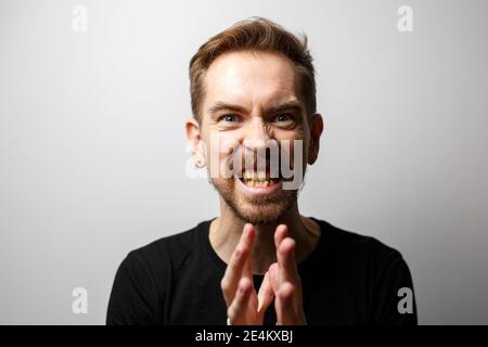 Wütend jungen Mann Porträt auf einem grauen Hintergrund Stockfoto