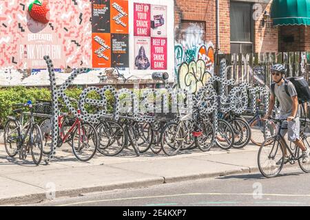 Toronto, Kanada - 26/07/2019 - Fahrräder geparkt und ein Fahrer vorbei in Kensignton Markt Stockfoto