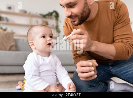 Liebevoller Junger Vater Löffel Fütterung Sein Kleines Baby Sitzt Im Innen Stockfoto