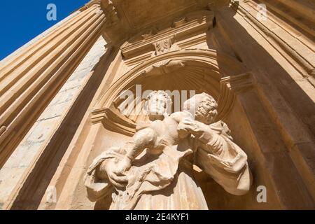 Skulptur des Mönchs mit Kind in den Armen in barocken Außentür der Pfarrei Santa Ana, Wahrzeichen und Denkmal in Penaranda de Duero, Burgos, Kastilien an Stockfoto