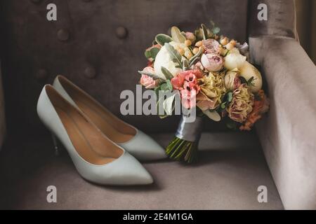 Weiße Brautschuhe und ein Blumenstrauß. Stockfoto