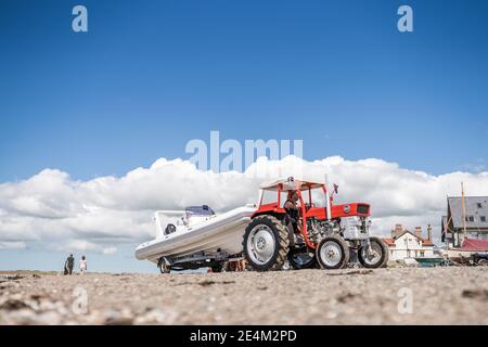 Schlepper Schleppen Schnellboot aus dem Meer in Nord-Wales sandig Strand vom Meer rot weiß Schnellboot glänzend sauber sonnig Sumer Tag am Meer mit Booten Hintergrund Stockfoto