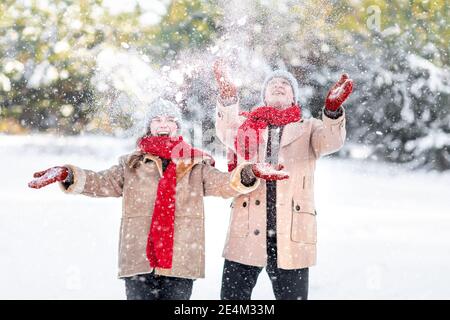 Fröhlicher junger Mann und Frau genießen Schnee am Wintertag Stockfoto
