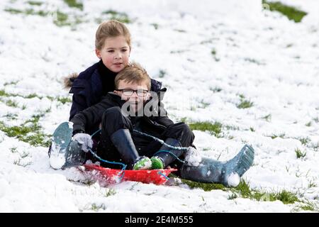 Chippenham, Wiltshire, Großbritannien. Januar 2021. Als Chippenham Bewohner zu ihrem ersten Schnee des Jahres aufwachen, werden zwei Kinder in einem lokalen Park in Chippenham abgebildet, während sie auf einem Schlitten einen Hügel hinuntergleiten. Quelle: Lynchpics/Alamy Live News Stockfoto