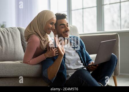 Liebevolle Mitte östlichen Paar mit Laptop, mit Online-Party Stockfoto