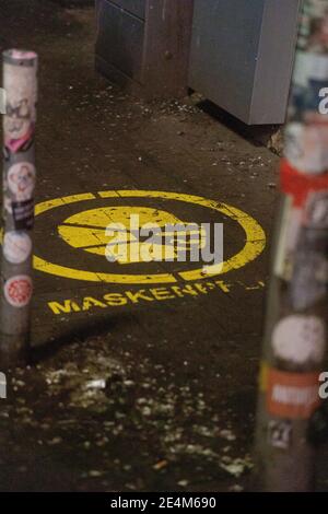 Deutsches Zeichen auf dem Boden eines öffentlichen Raumes beantragt Dass Menschen Masken tragen Stockfoto