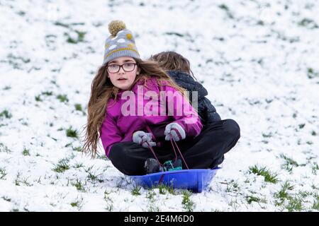 Chippenham, Wiltshire, Großbritannien. Januar 2021. Als Chippenham Bewohner zu ihrem ersten Schnee des Jahres aufwachen, werden zwei Kinder in einem lokalen Park in Chippenham abgebildet, während sie auf einem Schlitten einen Hügel hinuntergleiten. Quelle: Lynchpics/Alamy Live News Stockfoto