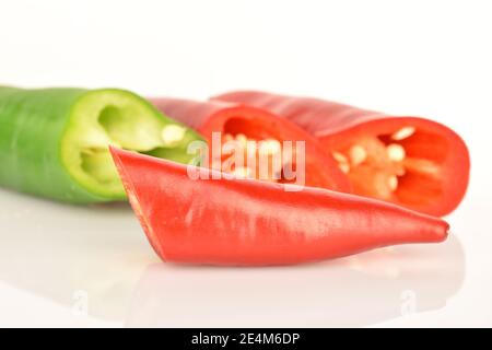 Drei kurze würzige frisch reife Paprika, rot und grün, auf weißem Hintergrund. Im Vordergrund im Fokus, Makro, geschnittene Spitze von rotem Pfeffer. Stockfoto