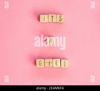 Es ist ein Mädchen Text geschrieben mit Holzwürfeln auf pastellweißem Hintergrund Draufsicht, Baby Ankündigung. Flaches Lay-Format, Textbereich. Grußkarte, Dusche, Baby Stockfoto