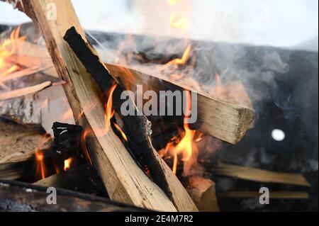 Nahaufnahme von brennendem und rauchendem Holz in schmiedeeisernem Brazier im Winter. Sicherer Brand. Kochen im Freien. Stockfoto