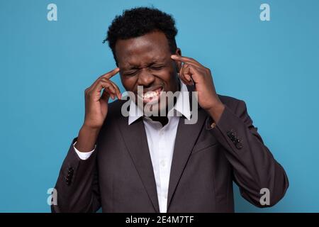 Gestresster junger afroamerikanischer Mann fühlt Schmerzen mit schrecklichen starken Kopfschmerzen. Müde aufgeregt schwarzen Kerl massieren Tempel leiden an Migräne. Stockfoto