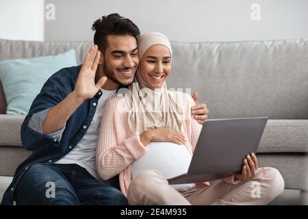 Glücklich Schwanger Muslim Paar Machen Video Anruf Mit Laptop Bei Zu Hause Stockfoto