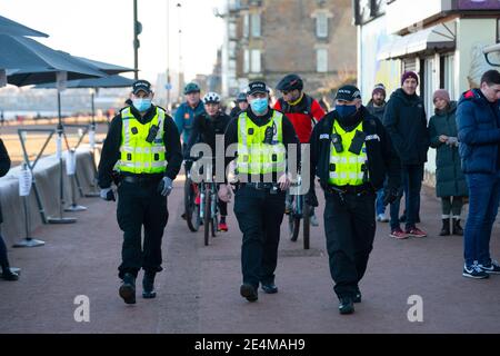 Portobello, Schottland, Großbritannien. 24. Januar 2021. Große Anzahl von Mitgliedern der Öffentlichkeit am Portobello Strand und Promenade am sonnigen Sonntagnachmittag während der Sperre. Während die meisten Menschen beobachtet soziale distanzierende Gruppen von Menschen in einigen der Cafés mit Essen und Getränken zum Mitnehmen gebildet. Polizeipatrouillen sprachen mit den öffentlichen Sitzen und in Gruppen in Cafés, um sie zu bitten, weiter zu gehen. Iain Masterton/Alamy Live News Stockfoto