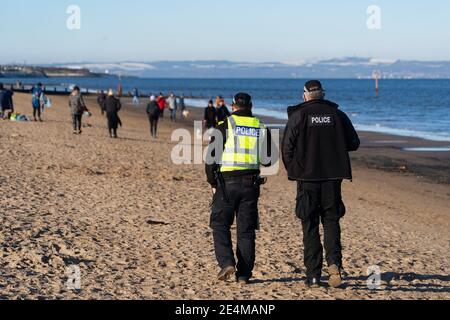 Portobello, Schottland, Großbritannien. 24. Januar 2021. Große Anzahl von Mitgliedern der Öffentlichkeit am Portobello Strand und Promenade am sonnigen Sonntagnachmittag während der Sperre. Während die meisten Menschen beobachtet soziale distanzierende Gruppen von Menschen in einigen der Cafés mit Essen und Getränken zum Mitnehmen gebildet. Polizeipatrouillen sprachen mit den öffentlichen Sitzen und in Gruppen in Cafés, um sie zu bitten, weiter zu gehen. Iain Masterton/Alamy Live News Stockfoto