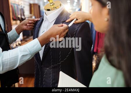 Nahaufnahme von Schneidern, die Details des maßgeschneiderten Jackenkragens besprechen Bei der Arbeit im Atelier Stockfoto